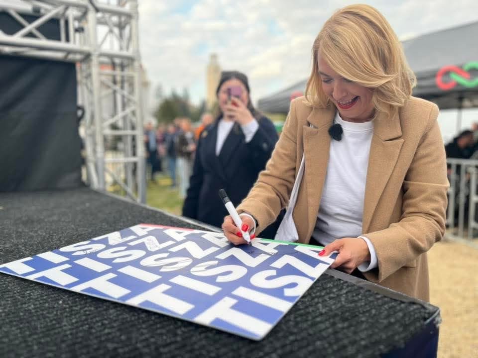 Tompa Enikő dedikálja a tiszás plakátokat